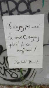 Photo d'une affiche collée sur un mur sur laquelle est écrit "Ne craignez pas ainsi la mort, craignez plutôt la vie insuffisante ! Berthold Brecht" 
